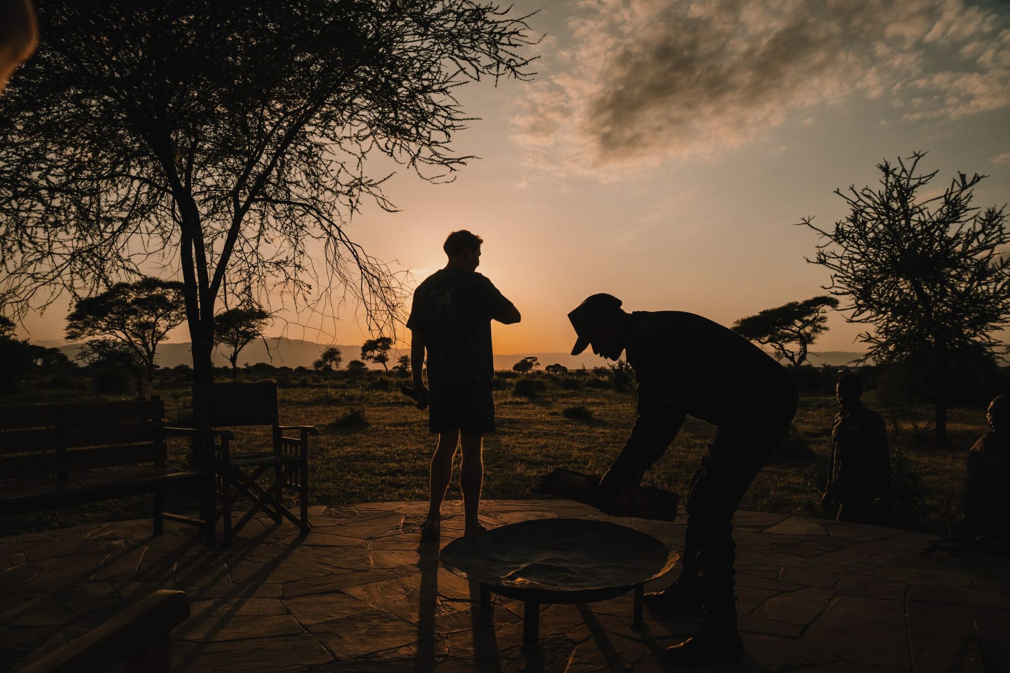 Sonnenuntergang im Tarangire-Nationalpark, auf der Terrasse wird Holz in die Feuerschale gelegt