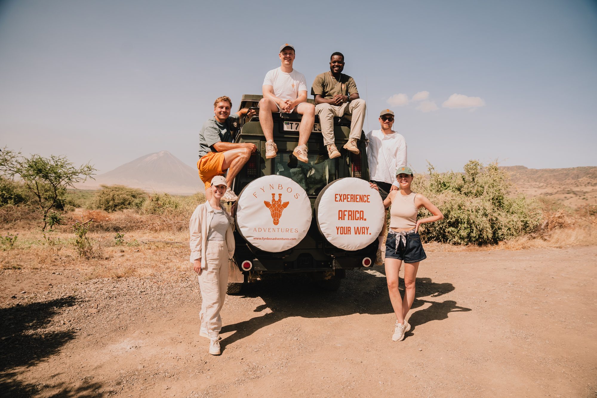 Die ganze Gruppe sitzt auf und vor dem Fynbos-Geländewagen