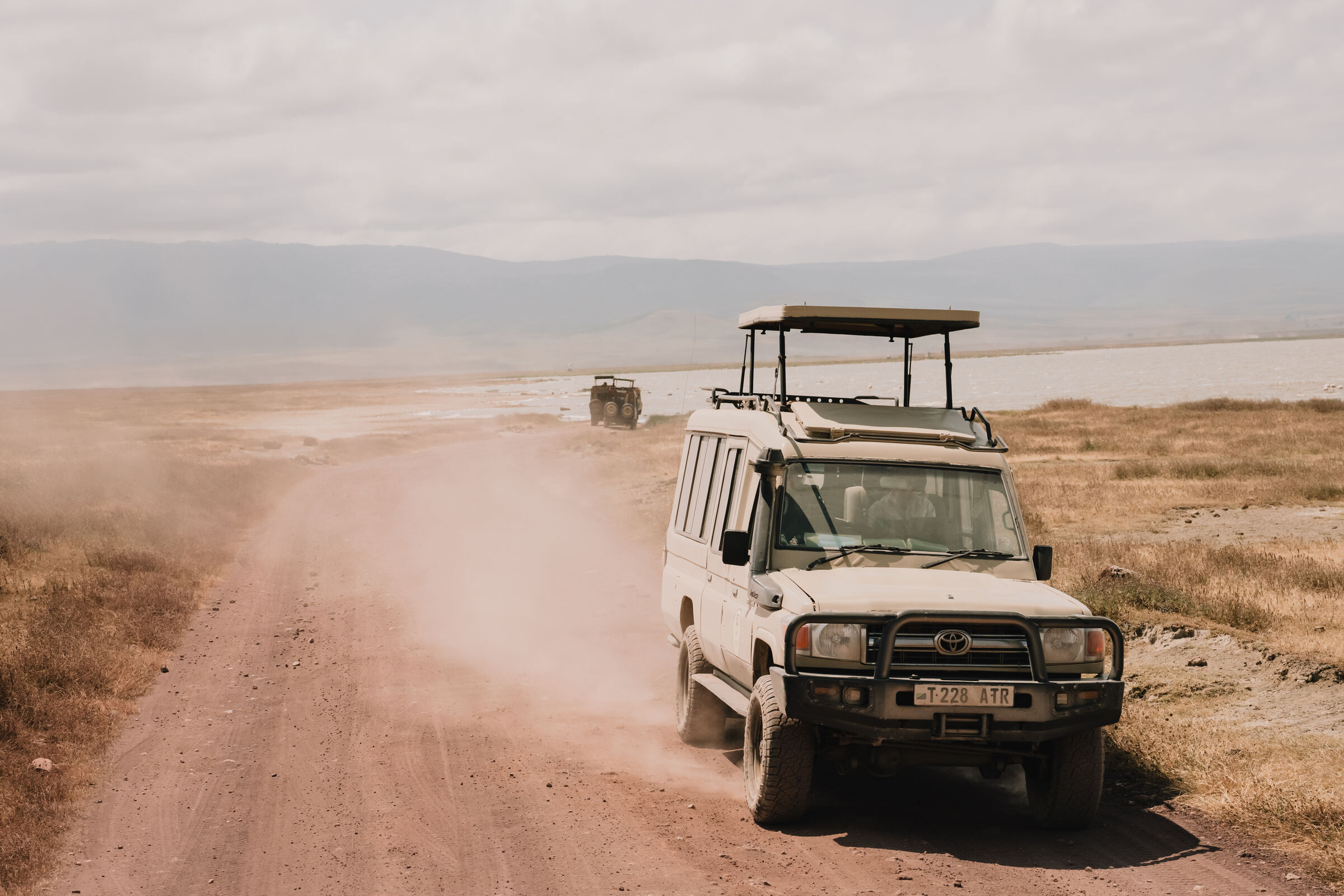 Geländewagen fährt auf einer staubigen Piste durch den Ngorongoro-Krater