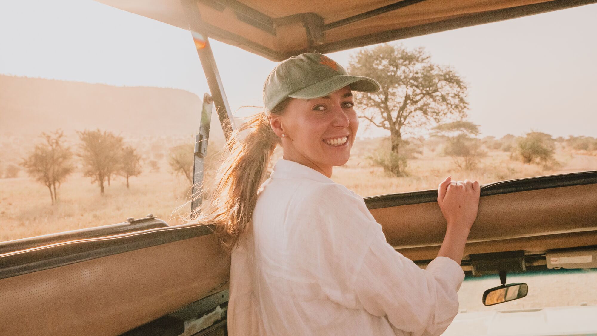 Reisende mit grüner Kappe im offenen Fahrzeug in der Serengeti